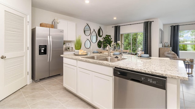 kitchen with stainless steel appliances, a sink, white cabinetry, an island with sink, and light tile patterned floors