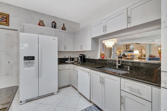7829 Mansfield Hollow Rd, Delray Beach, FL 33446 - kitchen featuring dark stone countertops, a sink, white appliances, a chandelier, and white cabinetry