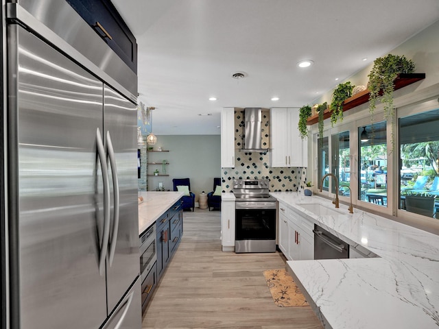 3821 NE 29th Ave, Lighthouse Point, FL 33064 - kitchen featuring appliances with stainless steel finishes, wall chimney range hood, a sink, white cabinetry, and recessed lighting