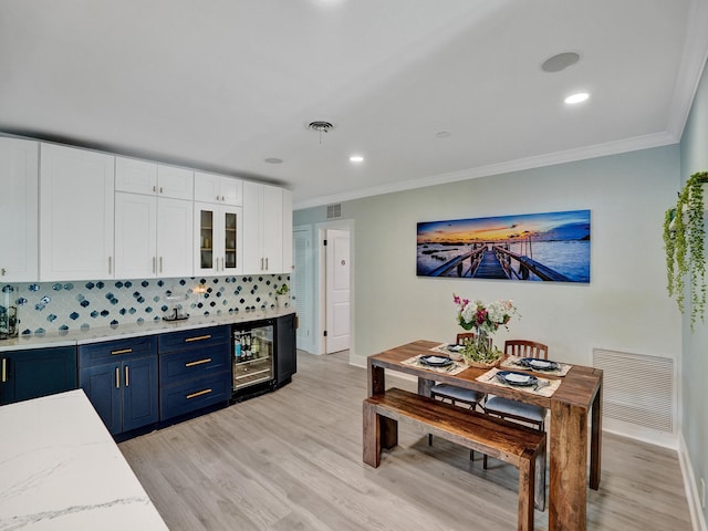 3821 NE 29th Ave, Lighthouse Point, FL 33064 - kitchen with blue cabinetry, beverage cooler, white cabinetry, ornamental molding, and light wood-type flooring