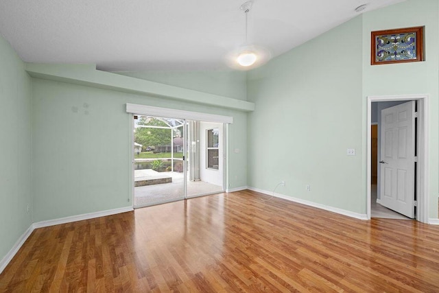 unfurnished room featuring wood finished floors, high vaulted ceiling, and baseboards