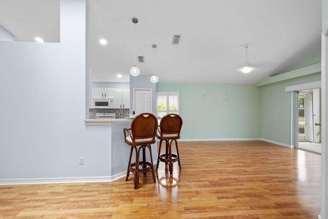 kitchen with light wood finished floors, white microwave, white cabinets, and visible vents