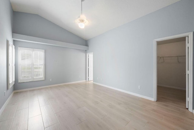 spare room featuring baseboards, vaulted ceiling, and light wood-type flooring