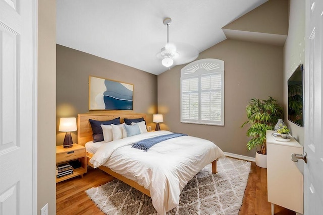 bedroom featuring lofted ceiling, wood finished floors, and baseboards