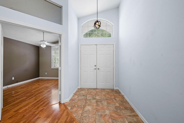 entryway with stone finish flooring, a high ceiling, and baseboards