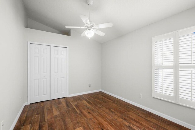 unfurnished bedroom with wood finished floors, multiple windows, lofted ceiling, and a closet