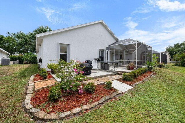 back of house featuring a patio area, a lanai, a lawn, stucco siding, and central AC