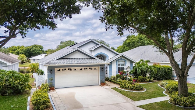 single story home with stucco siding, driveway, roof with shingles, a front lawn, and an attached garage