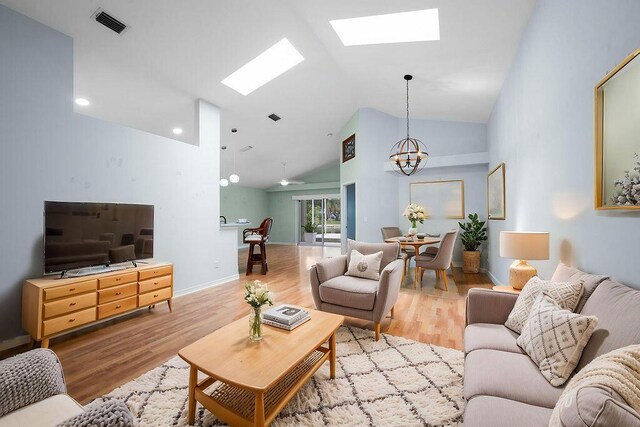 living room with wood finished floors, visible vents, a notable chandelier, and a skylight