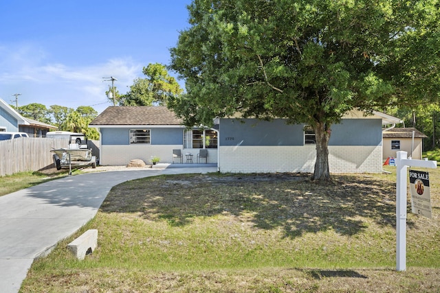 1728 SE Harrison St, Stuart, FL 34997 - view of front of house featuring concrete driveway, fence, a front yard, and stucco siding