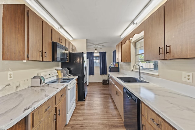 1728 SE Harrison St, Stuart, FL 34997 - kitchen featuring ceiling fan, brown cabinetry, a sink, black appliances, and light wood-style floors