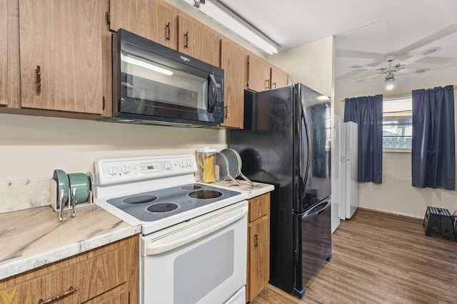 1728 SE Harrison St, Stuart, FL 34997 - kitchen with light wood-type flooring, light countertops, brown cabinets, a ceiling fan, and black appliances