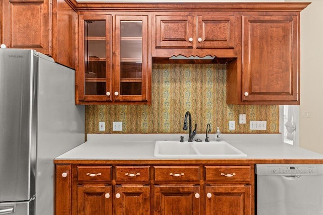 kitchen with light countertops, appliances with stainless steel finishes, glass insert cabinets, and a sink