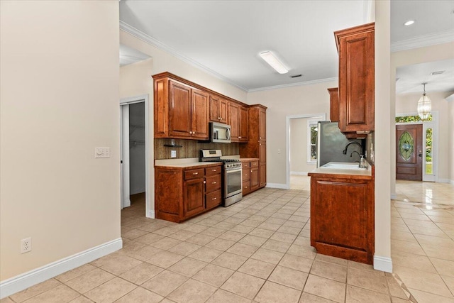 kitchen with appliances with stainless steel finishes, a sink, light countertops, light tile patterned floors, and backsplash