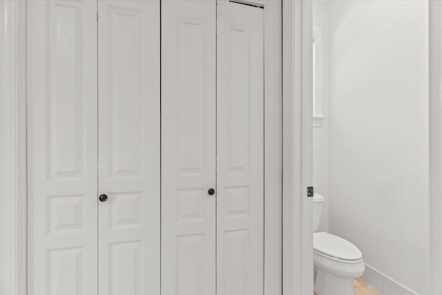 bathroom with a closet, baseboards, and toilet