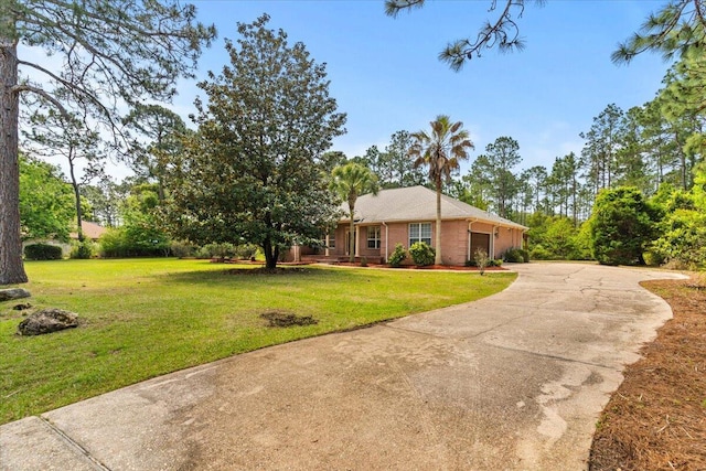 single story home featuring an attached garage, driveway, a front lawn, and brick siding