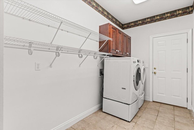 washroom with baseboards, washing machine and dryer, cabinet space, and light tile patterned flooring