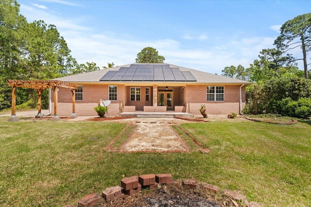 back of property featuring brick siding, a yard, a pergola, and solar panels