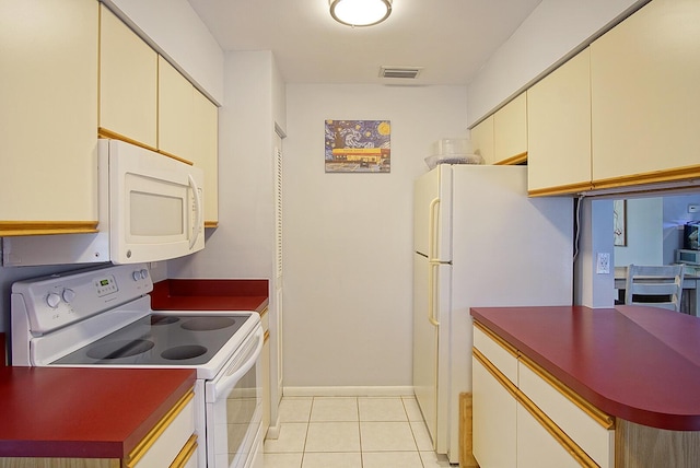 5620 SE Paramount Dr, Stuart, FL 34997 - kitchen featuring white appliances, light tile patterned floors, dark countertops, visible vents, and cream cabinetry