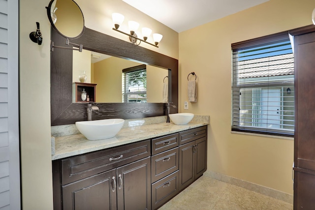 bathroom with baseboards, a sink, tile patterned floors, and double vanity