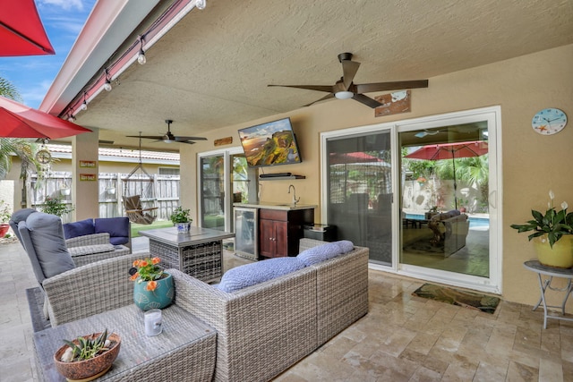 view of patio featuring a ceiling fan, a sink, beverage cooler, and an outdoor hangout area