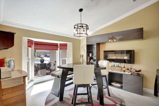 dining space featuring a notable chandelier, a textured ceiling, tile patterned floors, vaulted ceiling, and ornamental molding