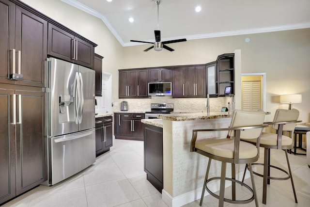 kitchen featuring crown molding, light stone counters, stainless steel appliances, a ceiling fan, and backsplash