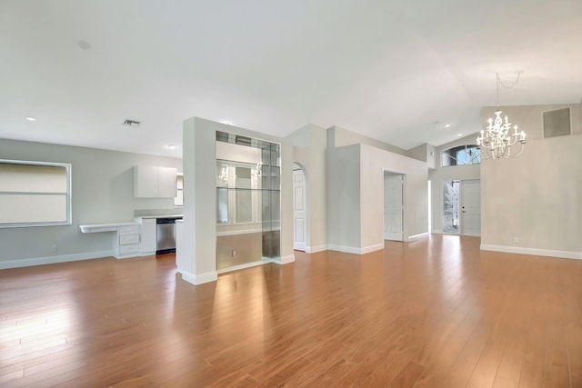 unfurnished living room with vaulted ceiling, wood finished floors, baseboards, a notable chandelier, and recessed lighting
