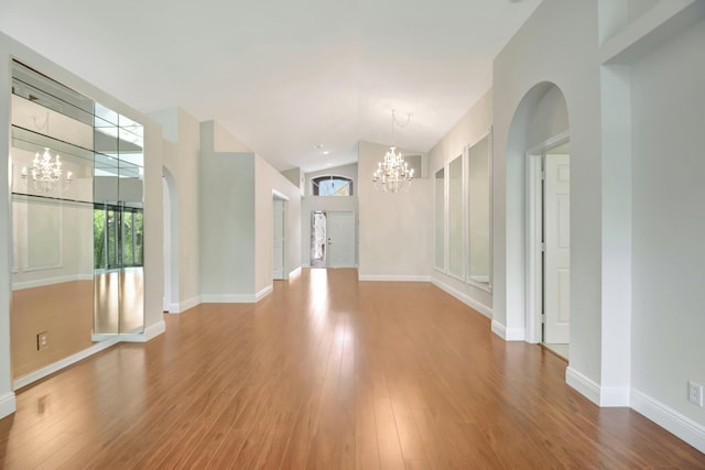 interior space with lofted ceiling, a notable chandelier, wood finished floors, and baseboards
