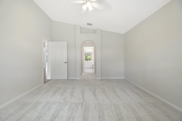 unfurnished room featuring arched walkways, visible vents, baseboards, light colored carpet, and a ceiling fan