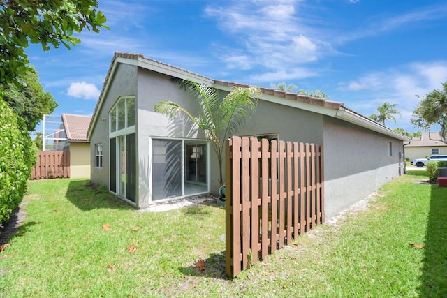 exterior space featuring stucco siding, fence, and a lawn