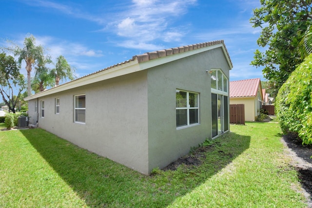 view of property exterior featuring stucco siding, a yard, and central AC