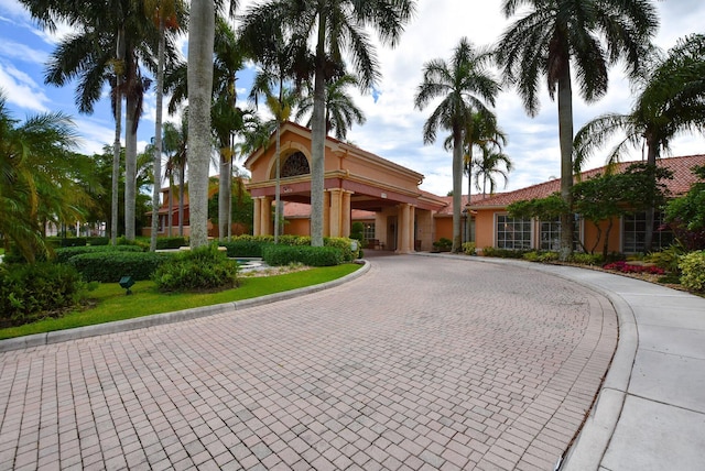 view of front of home with a tile roof, curved driveway, and stucco siding