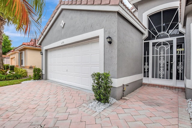 exterior space featuring stucco siding, decorative driveway, and a tiled roof