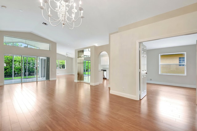 unfurnished living room with arched walkways, a chandelier, wood finished floors, and lofted ceiling