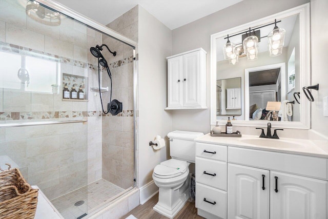 bathroom with vanity, toilet, wood finished floors, and a shower stall