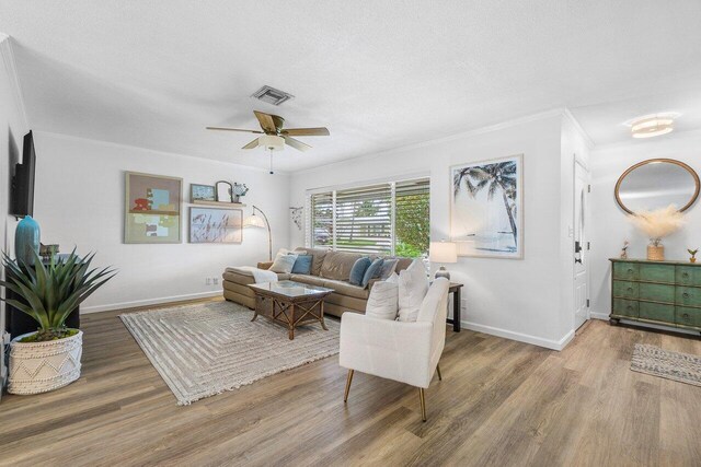 living area featuring crown molding, visible vents, wood finished floors, and a ceiling fan