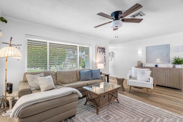 living room featuring ceiling fan, crown molding, visible vents, and wood finished floors