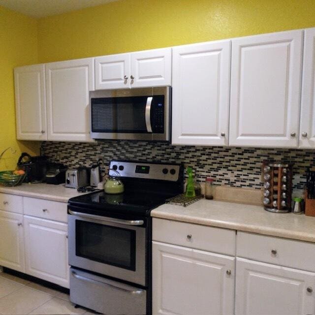 3101 N Evergreen Cir N, Boynton Beach, FL 33426 - kitchen with appliances with stainless steel finishes, backsplash, white cabinetry, and light countertops