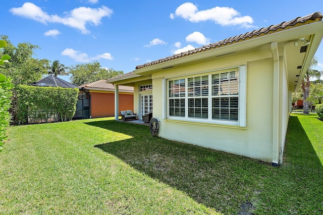 exterior space with a yard, a tile roof, and stucco siding