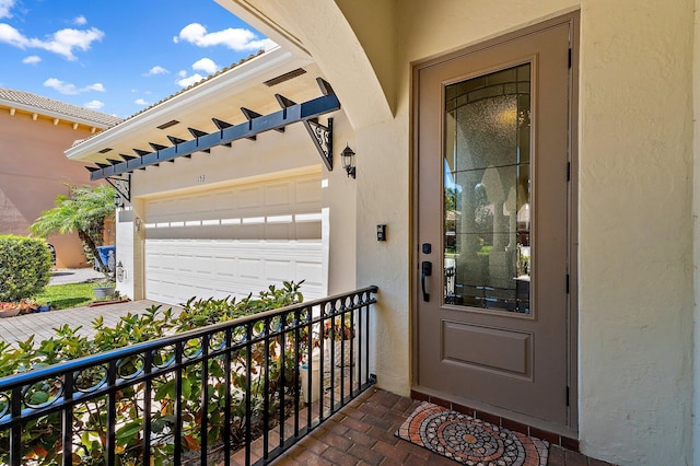 doorway to property featuring a garage, stucco siding, and a balcony