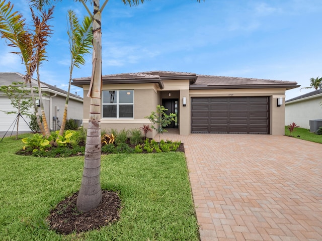 13509 SW Oceanus Blvd, Port Saint Lucie, FL 34987 - prairie-style home featuring stucco siding, decorative driveway, an attached garage, a front lawn, and a tiled roof