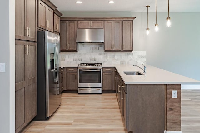 13509 SW Oceanus Blvd, Port Saint Lucie, FL 34987 - kitchen with stainless steel appliances, range hood, a sink, a peninsula, and light wood finished floors