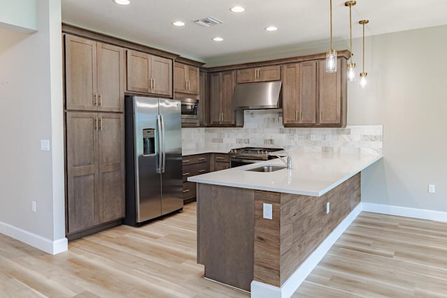 13509 SW Oceanus Blvd, Port Saint Lucie, FL 34987 - kitchen featuring stainless steel appliances, under cabinet range hood, baseboards, a peninsula, and recessed lighting