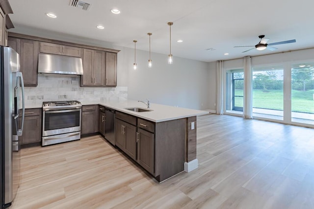 13509 SW Oceanus Blvd, Port Saint Lucie, FL 34987 - kitchen with stainless steel appliances, under cabinet range hood, a sink, a ceiling fan, and tasteful backsplash