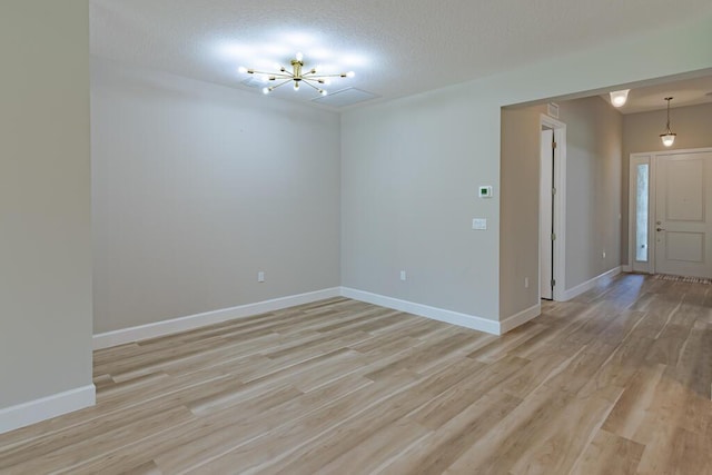 13509 SW Oceanus Blvd, Port Saint Lucie, FL 34987 - unfurnished room featuring light wood-style floors, a chandelier, a textured ceiling, and baseboards