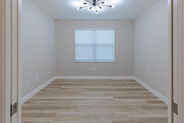13509 SW Oceanus Blvd, Port Saint Lucie, FL 34987 - empty room with a chandelier, light wood-style floors, and baseboards