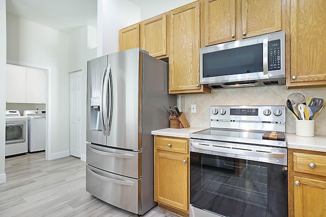 kitchen featuring light countertops, appliances with stainless steel finishes, decorative backsplash, and washing machine and clothes dryer