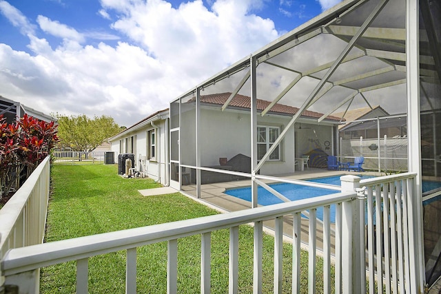 view of swimming pool featuring a patio, a fenced backyard, a fenced in pool, a lawn, and glass enclosure