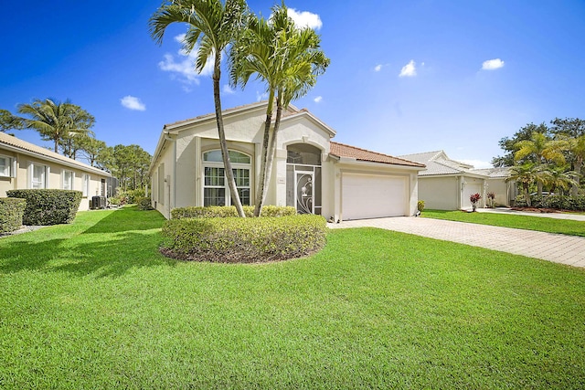 mediterranean / spanish house featuring a front lawn, decorative driveway, stucco siding, an attached garage, and central air condition unit